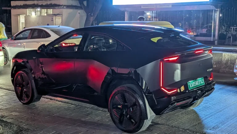 Black Mahindra BE 6 electric SUV with red C-shaped taillights on a Bengaluru street at night