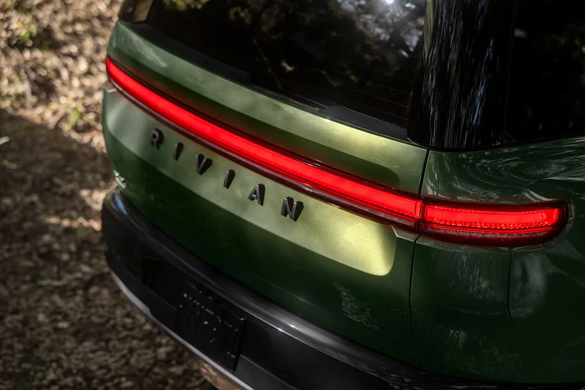 Rear of a Rivian R2 Forest Green with its full-width taillight lit