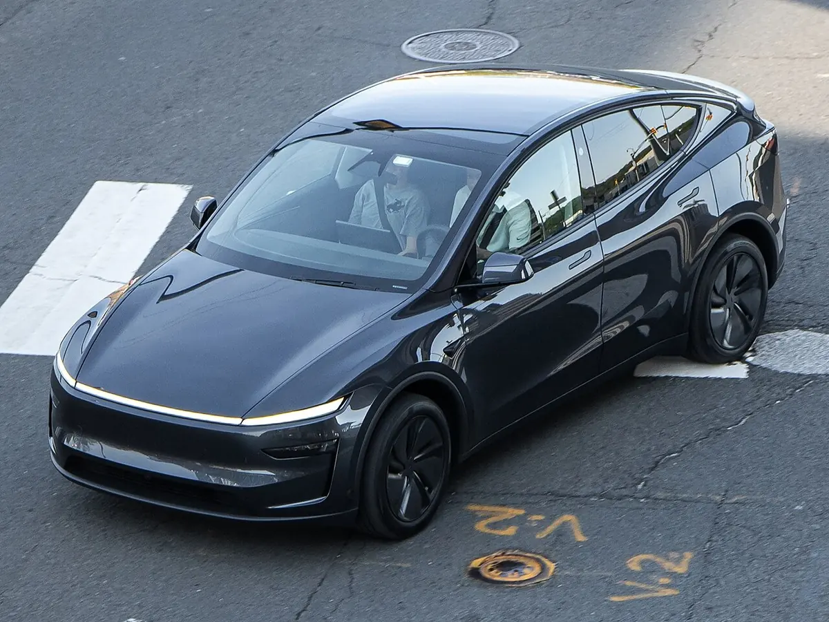 Dark gray Tesla Model Y crossing a city street, one of the models in the reported Tesla lease price increase and APR change