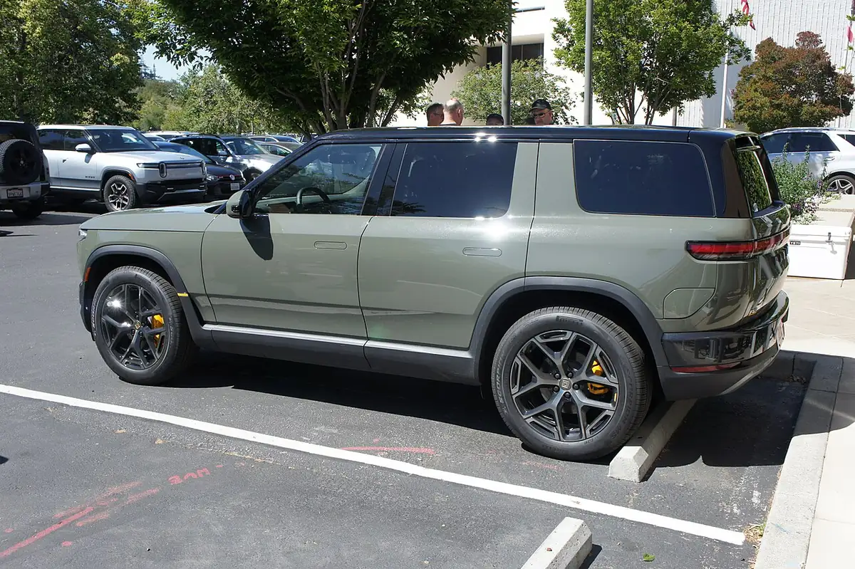 Side and rear view of a Launch Green Rivian R2 in a parking lot